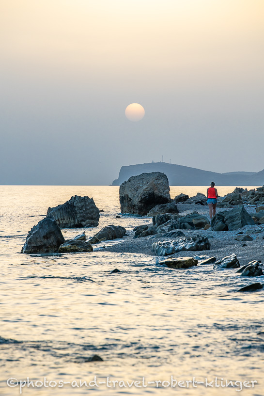 A woman walking along a beach in Albania during sunset