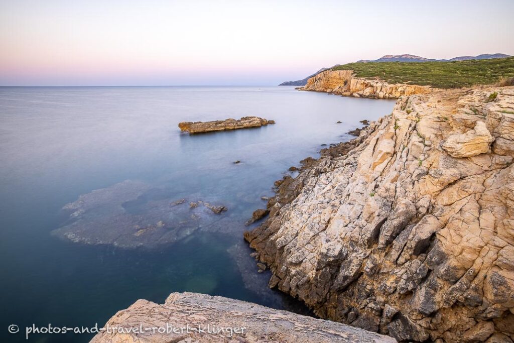 Long exposure photo of a sunrise on a stony and steep shore in Greece