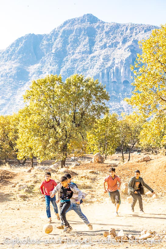 Five boys playing soccer on a field in northern Kurdistan