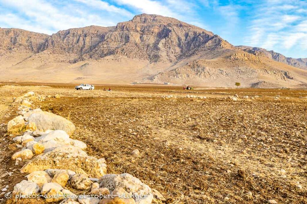 A tractor in the wide landscape of Kurdistan at lake Dukan, a mountain range in the background