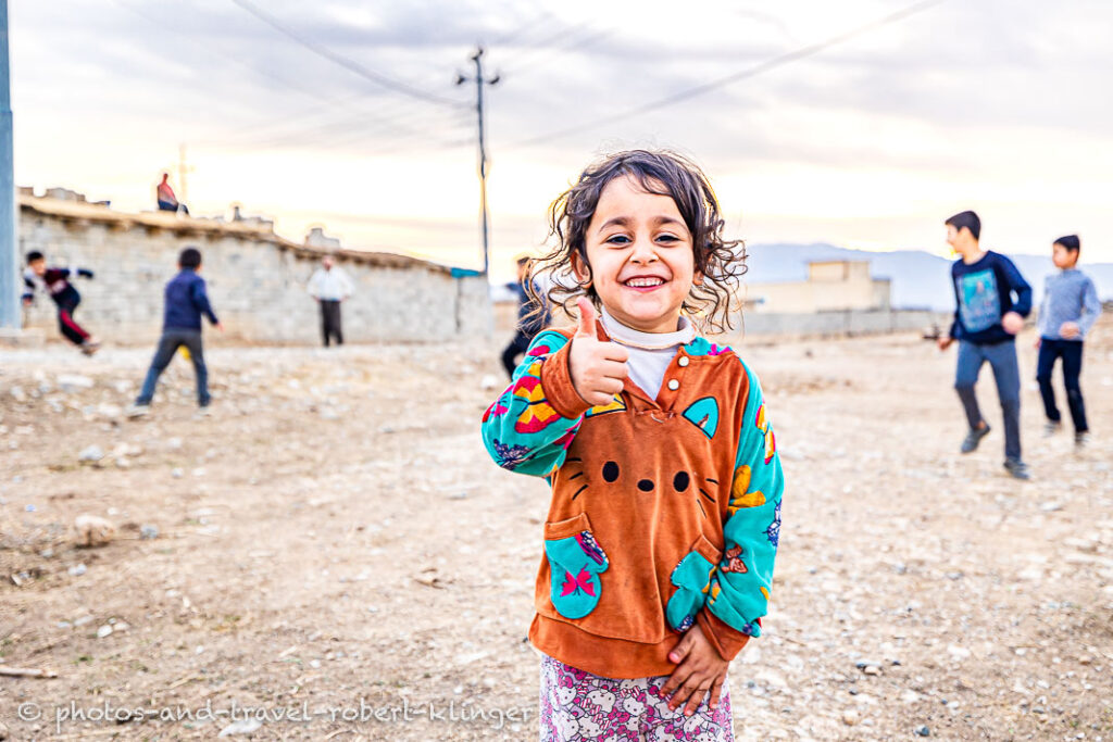 A girl showing her thump up in Kurdistan during a soccer game with other children
