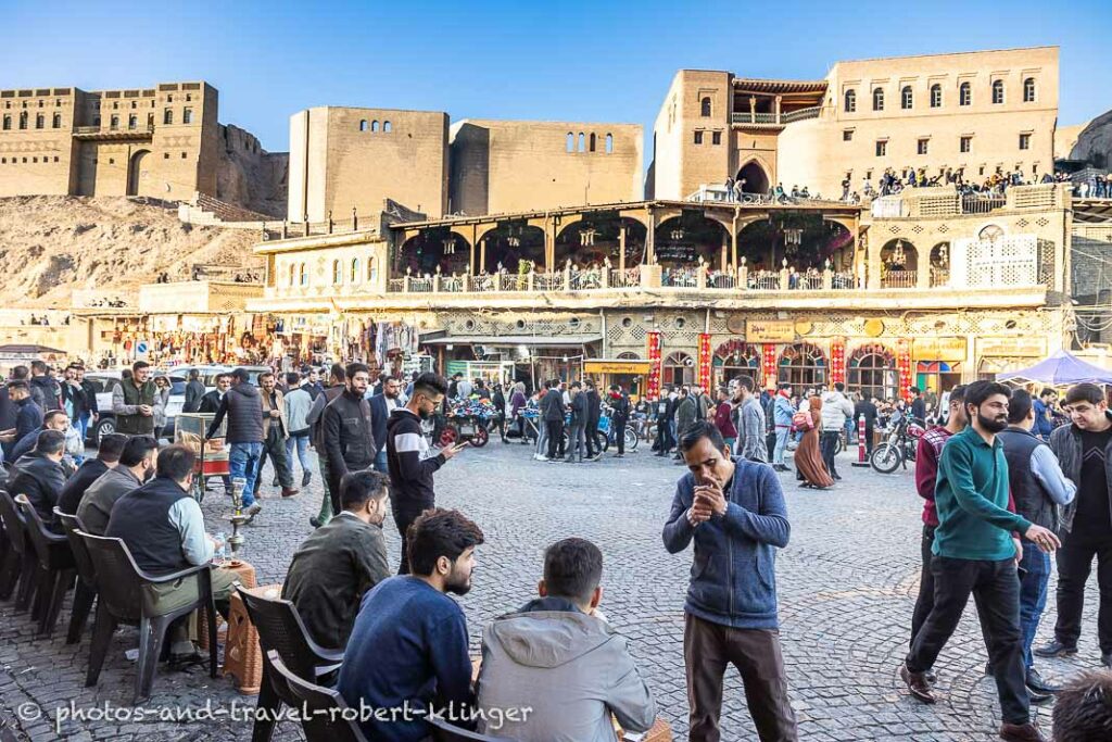 A man lighting a cigarette on the street in front of Erbils Citadel